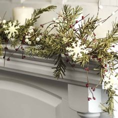 some white flowers and greenery on a mantle