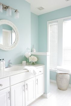 a bathroom with blue walls and white fixtures, including a large mirror above the sink