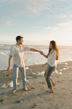 a man and woman holding hands on the beach