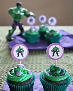 the cupcakes are decorated with green frosting and purple icing, as well as an iron man figure