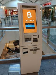 an atm machine with a bitcoin sign on it in the middle of a mall