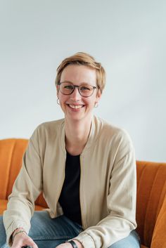 a smiling woman sitting on a couch holding a remote control