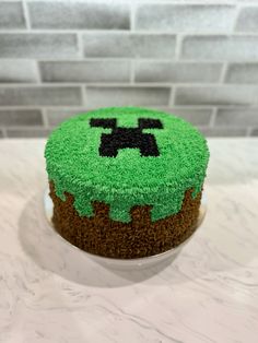 a cake decorated with green frosting and black icing on top of a counter