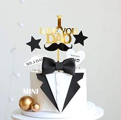 a white cake topped with a black bow tie and a gold topper that says i love you dad