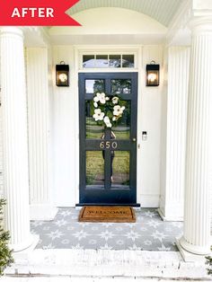 the front door is painted black and has white flowers on it, along with an entry mat