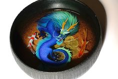 a blue dragon is sitting in a bowl with gold coins