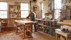 a man working in a wood shop with lots of workbenches and tools on the table