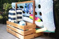 a wooden box filled with lots of items on top of a cement floor next to a fence