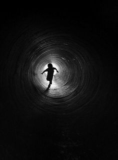 a person standing in the middle of a dark tunnel