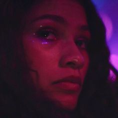 a close up of a person with purple light on their face and eyeliners