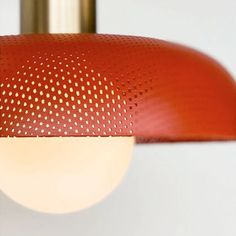 a close up of a light fixture with dots on it's red covering and a white wall in the background