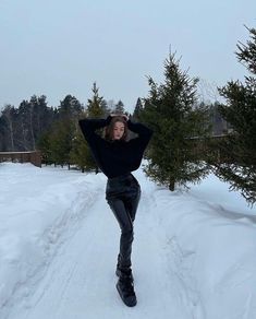 a woman is walking in the snow with her hands on her head