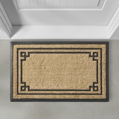 a beige door mat with a black border in the center on a gray floor next to a doorway