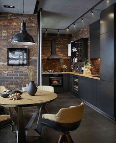 an industrial style kitchen and dining area with brick walls, black appliances and pendant lights