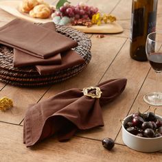 the table is set with napkins, wine glasses and grapes