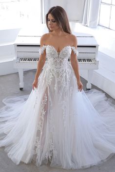 a woman standing in front of a piano wearing a white dress with flowers on it