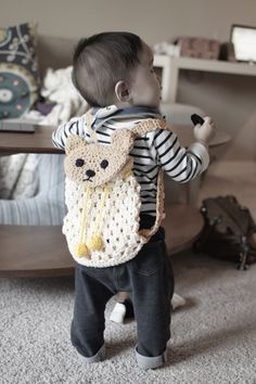 a small child with a crocheted bear backpack