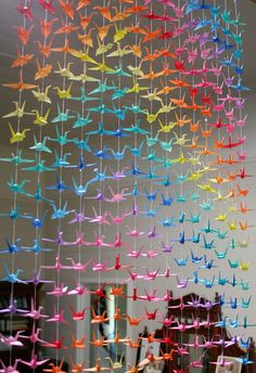 there are many colorful origami cranes hanging from the ceiling