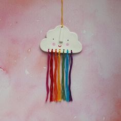 a white cloud hanging on a pink wall with rainbow streamers in the shape of a bear