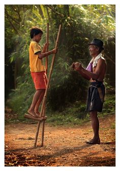 a man standing on top of a wooden pole next to a boy holding a stick