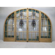 an arched wooden window with glass panes on the front and back sides, in a white room