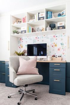 a chair in front of a desk with a computer on it and shelves behind it