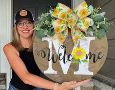 a woman holding up a welcome sign with sunflowers