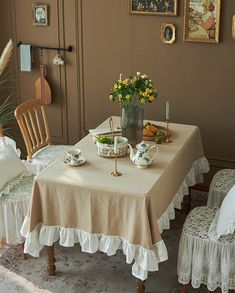 a dining room table covered in white ruffled linens with yellow flowers on it