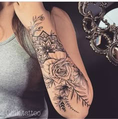 a woman's arm with flowers and leaves tattoo on her left arm, next to a mirror