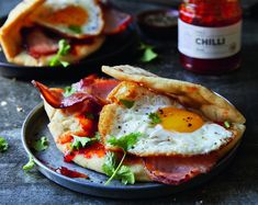 an egg and bacon pizza on a plate with ketchup