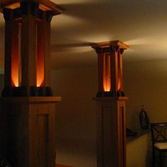 two tall wooden pillars with lights on them in a room next to a chair and table