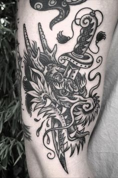 a black and white photo of a tattoo on someone's leg with a dragon