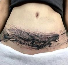 a woman's stomach with an artistic tattoo on it