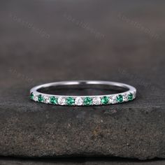 an emerald and diamond wedding band on a rock