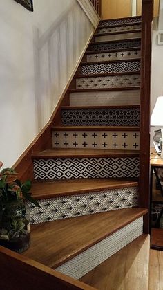 a stair case with decorative tiles on the bottom and sides, along with potted plants