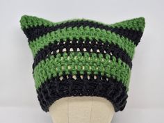 a green and black knitted cat hat on top of a mannequin head