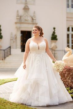 a woman in a wedding dress is walking down the sidewalk with her hand on her hip