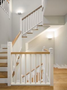 a white staircase with wooden handrails in a house