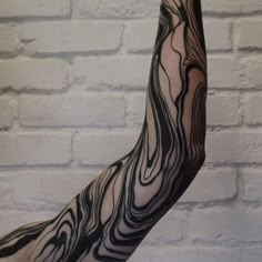 a person's arm with black and white ink on it in front of a brick wall