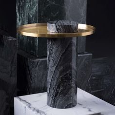 a marble table with a gold plate on top and black marble pedestals behind it