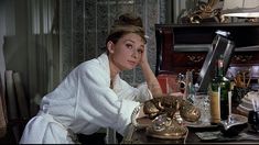 a woman sitting at a table in front of an old fashioned phone and other items