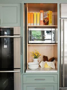 a kitchen with green cabinets and stainless steel appliances