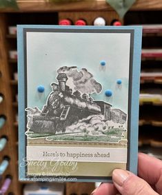 a hand holding up a card with a train on it and the words here's to happiness ahead