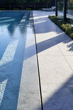 an empty swimming pool in the middle of a building with trees and bushes around it