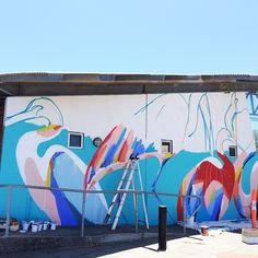 there is a mural painted on the side of a building with ladders next to it