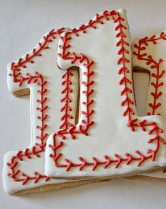 decorated cookies in the shape of baseball stitches are arranged to form the number ten on a white surface