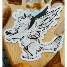 a sticker depicting a dog with wings on it's back, sitting on top of a wooden table