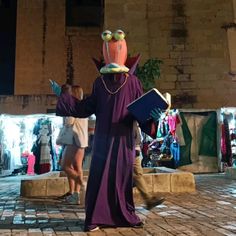 a man in a purple robe holding a book and wearing goggles on his head