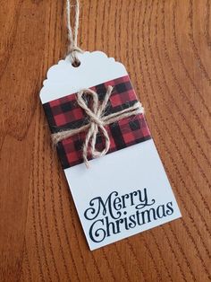 a merry christmas tag hanging on a wooden table with twine and burlock