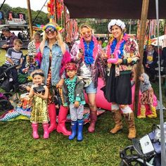 several women and children standing under a tent at an outdoor event, some wearing brightly colored clothing